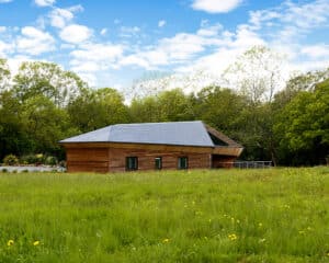 View across meadow to bedrooms at Brooks Barn, a Para 84 energy efficient passive house. Another grand design by Hawkes Architecture.